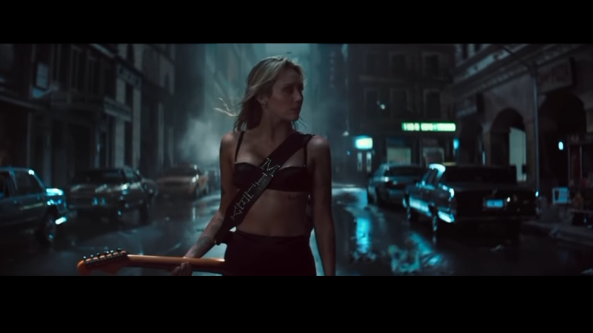 Miley wearing her custom Red Monkey guitar strap in the Bass Persuades video