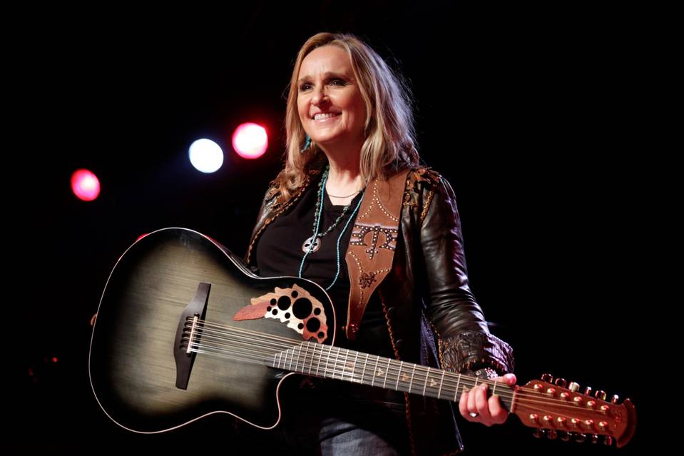 Melissa Etheridge performing with an acoustic guitar and Red Monkey leather guitar strap