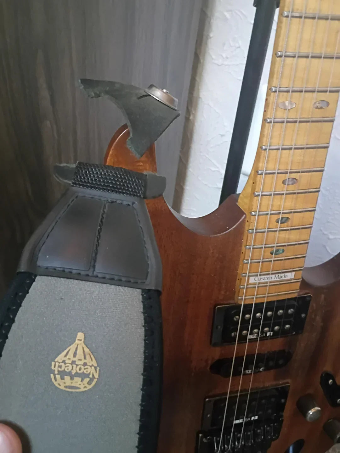 Broken guitar strap that failed at the mounting hole while attached to an electric guitar, illustrating a common failure of inexpensive guitar straps.